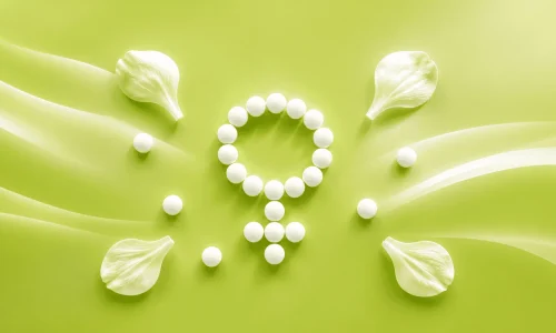kiwu-bonn-hormontherapie-header Weiße Tabletten in Form eines weiblichen Symbols auf grünem Hintergrund als Symbolbild für die Hormontherapie bei Kinderwunsch